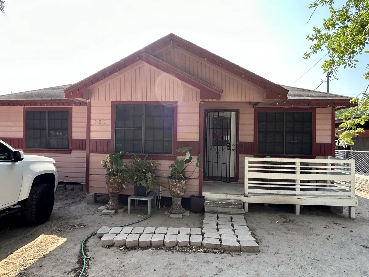 Home exterior before repair — faded pink siding with peeling paint