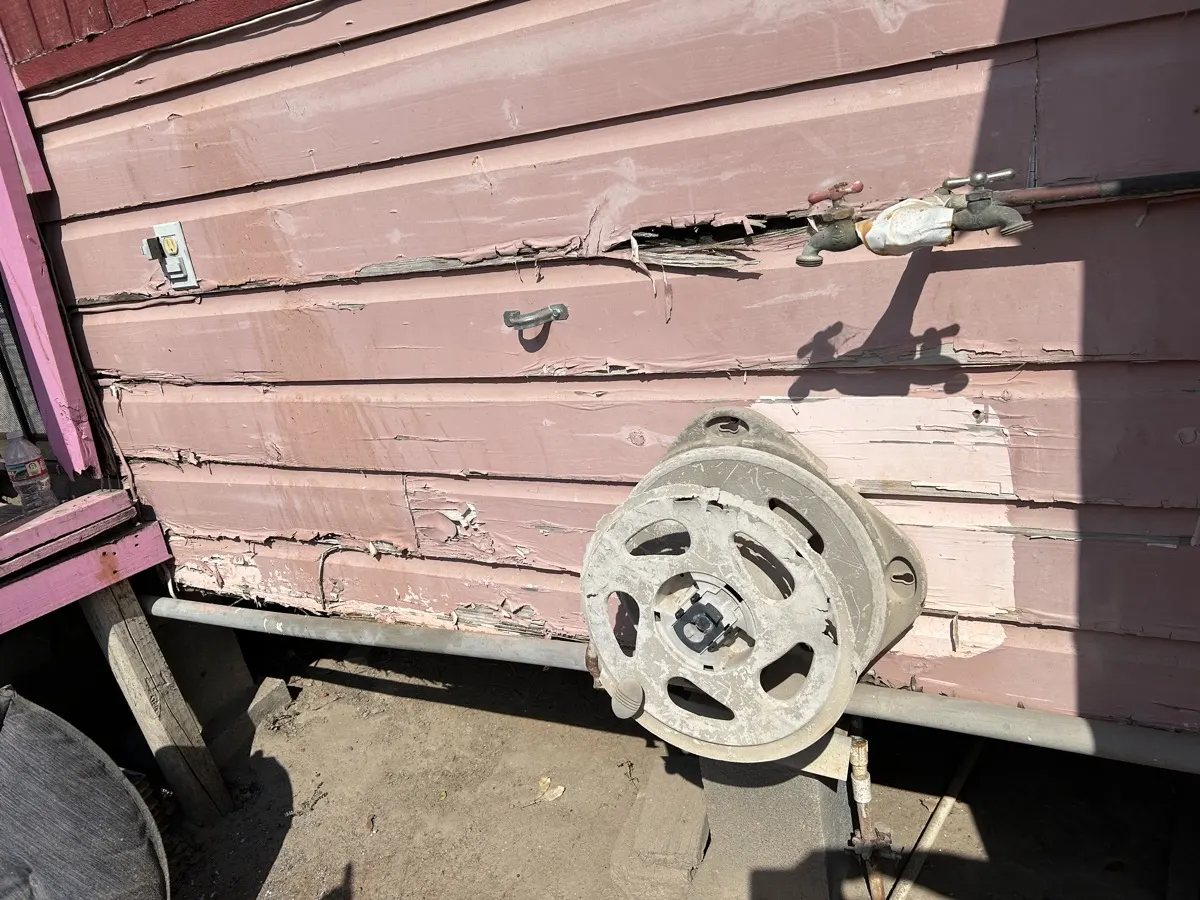 Exterior damage close-up — severely deteriorated siding
