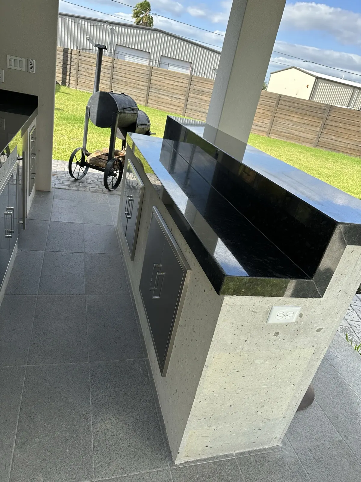 Finished outdoor kitchen — granite countertop island with built-in grill and smoker