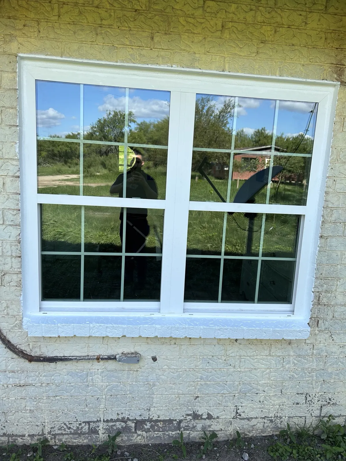 New window — exterior view showing grid-style window on yellow brick wall