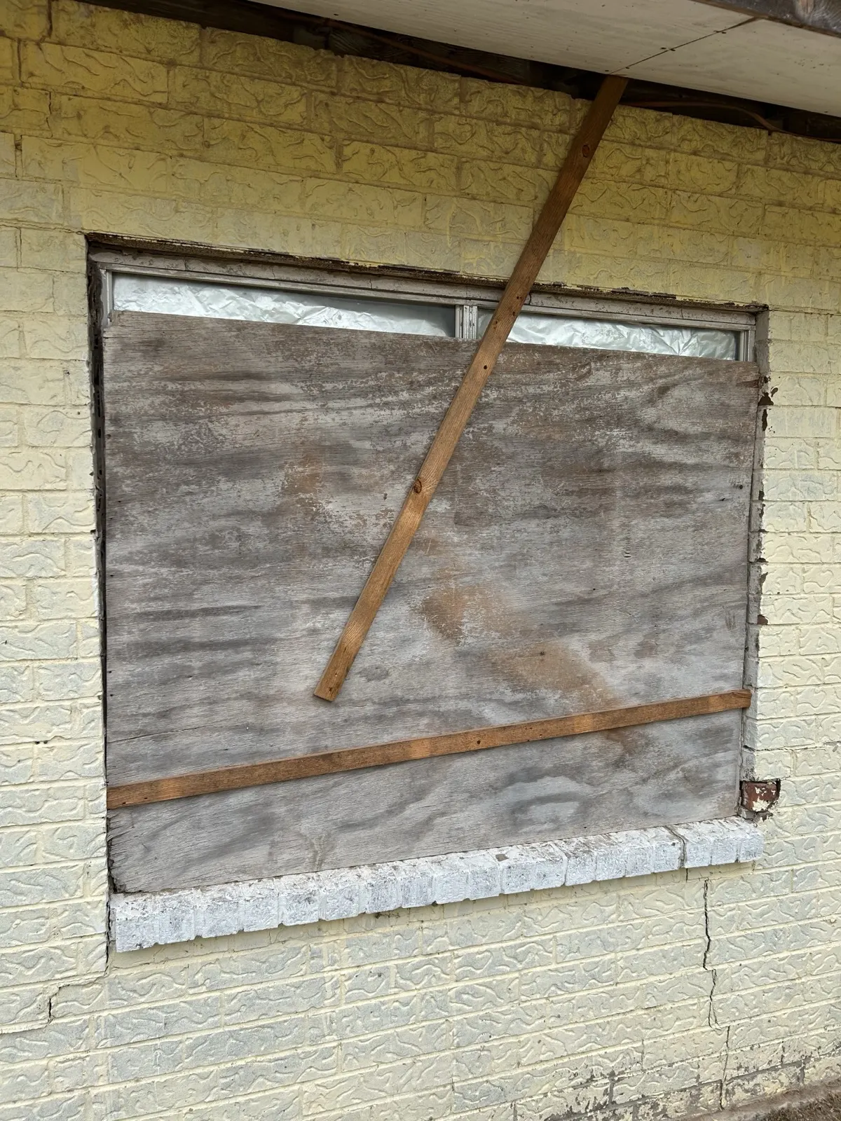 Window before replacement — boarded up with plywood